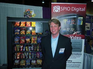 Dobbin Prezzano shows a device that dispenses redeemable promotions, along with digital video screens at the SPIO booth.