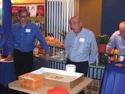 Brent Garson, left, introduces his father, Lester Garson, during the cake cutting at the 50th anniversary Vendors Exchange International open house.
