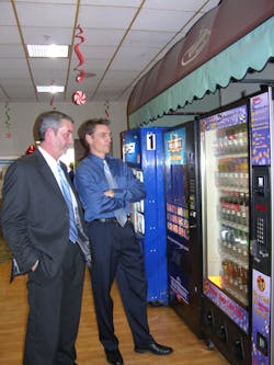 Colin Walsh, right, marketing director for Hometown/Tri-City Vending, came up with the idea of turning a glass front soda machine into a &lsquo;New Age Bevmart.&rsquo; &ldquo;My idea was to mirror what&rsquo;s happening in c-stores,&rdquo; said Walsh. With that in mind, Ken Martin, left, manager of the Peru location, has route drivers fill the machines with enhanced waters, milk, a few varieties of energy drinks and other beverages as well as soda.