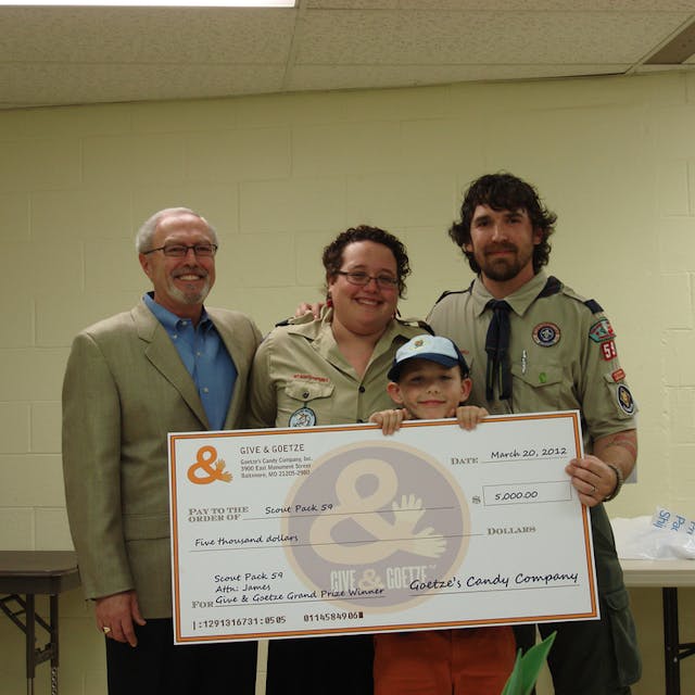 John Leipold, left, of Goetze presents the check to scout leaders Debbie and James Sanders and winning scout James Sanders, Jr.
