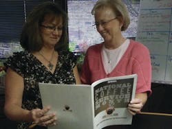 Linda Koch, left, of PrairieFire Coffee explains the Joe-on-the-Job Trivia Contest to Pam Martin of Emprise Bank.