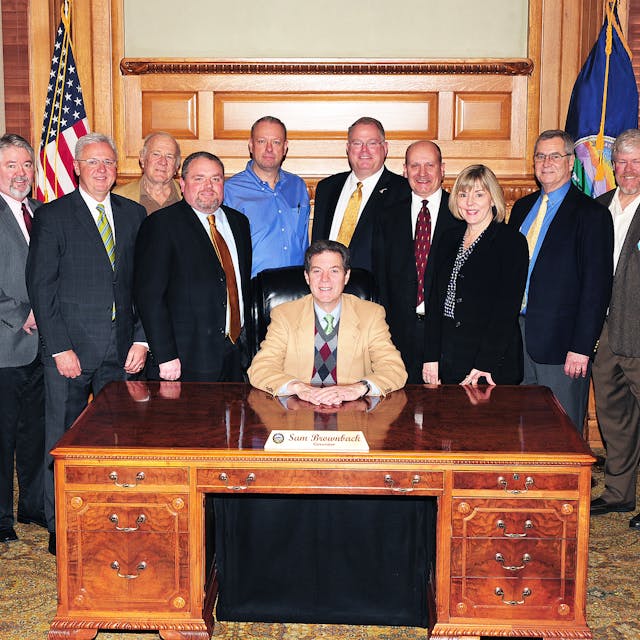 Kansas Governor Sam Brownback (center), surrounded by Mike Cox, John Barnes, Denny Burgess, Chip Stephenson, Joe Hemmelgarn, Claude Bockhold, Bill Bradford, Sandy Larson, Keith Bottorff and Tom Burgess.