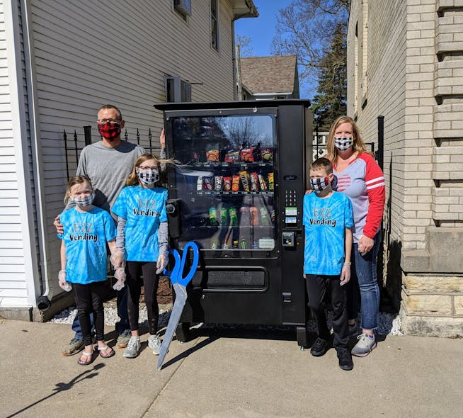 Emma Zrostlik and her family with their vending machine in Long Grove, Iowa, after a social distancing ribbon cutting