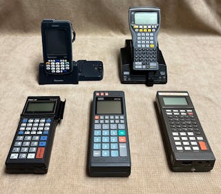 Telxon handheld (front left) with 2-line text display and proprietary operating system, a vending application introduced in 1988. Psion HC110 handheld (front center) with a monochrome graphic display, a vending application introduced in 1993. It was first handheld with an application for drivers, which could use DEX. Intermec handheld (front right) with 4-line monochrome text display, a vending application introduced in 1991. Intermec CN3 (back left) had a graphical color display and used Windows Mobile; this operating system was adopted by most handheld manufacturers and provided flexibility, a vending application introduced in 2008. Psion Workabout Pro handheld (back right) had a monochrome graphic display and ran proprietary operating system, a vending application introduced in 1998.