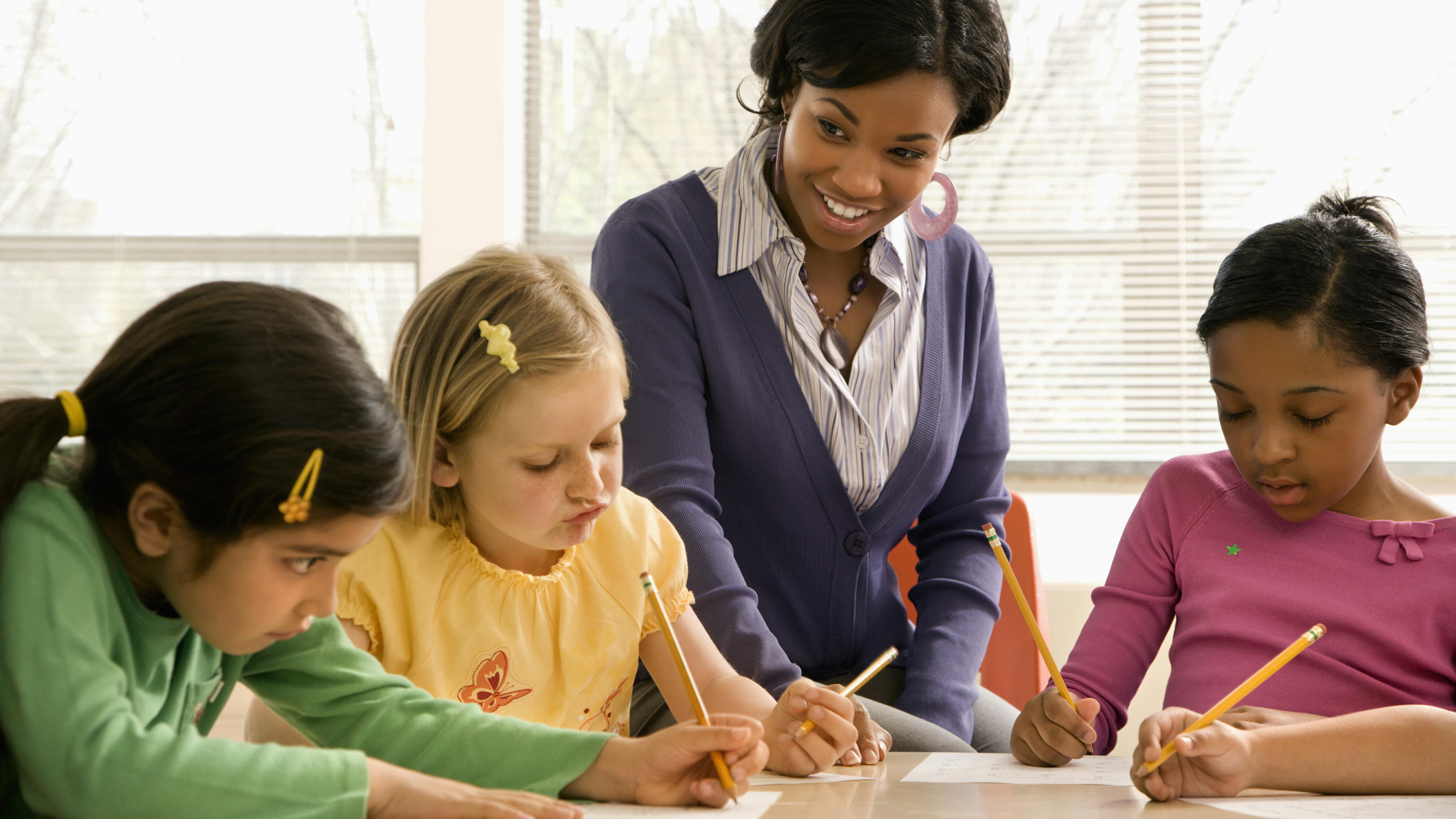 educator helping children classroom Iofoto | Dreamstime.com