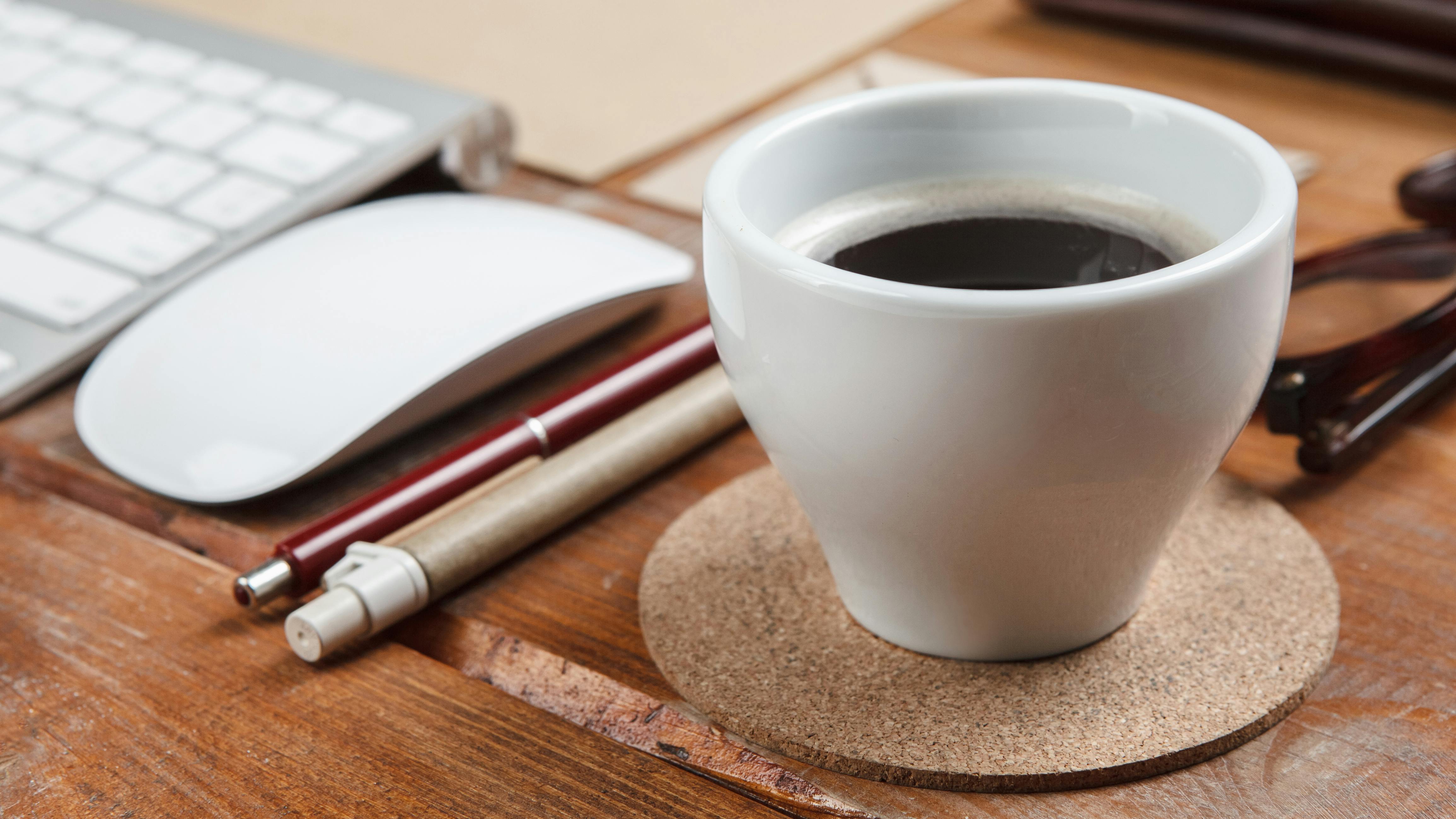 coffee cup, keyboard, mouse, pens, glasses stock image Freepik