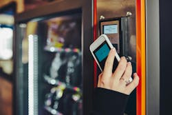 Woman paying for product at vending machine using smartphone. Woman paying for product at vending machine using smartphone.