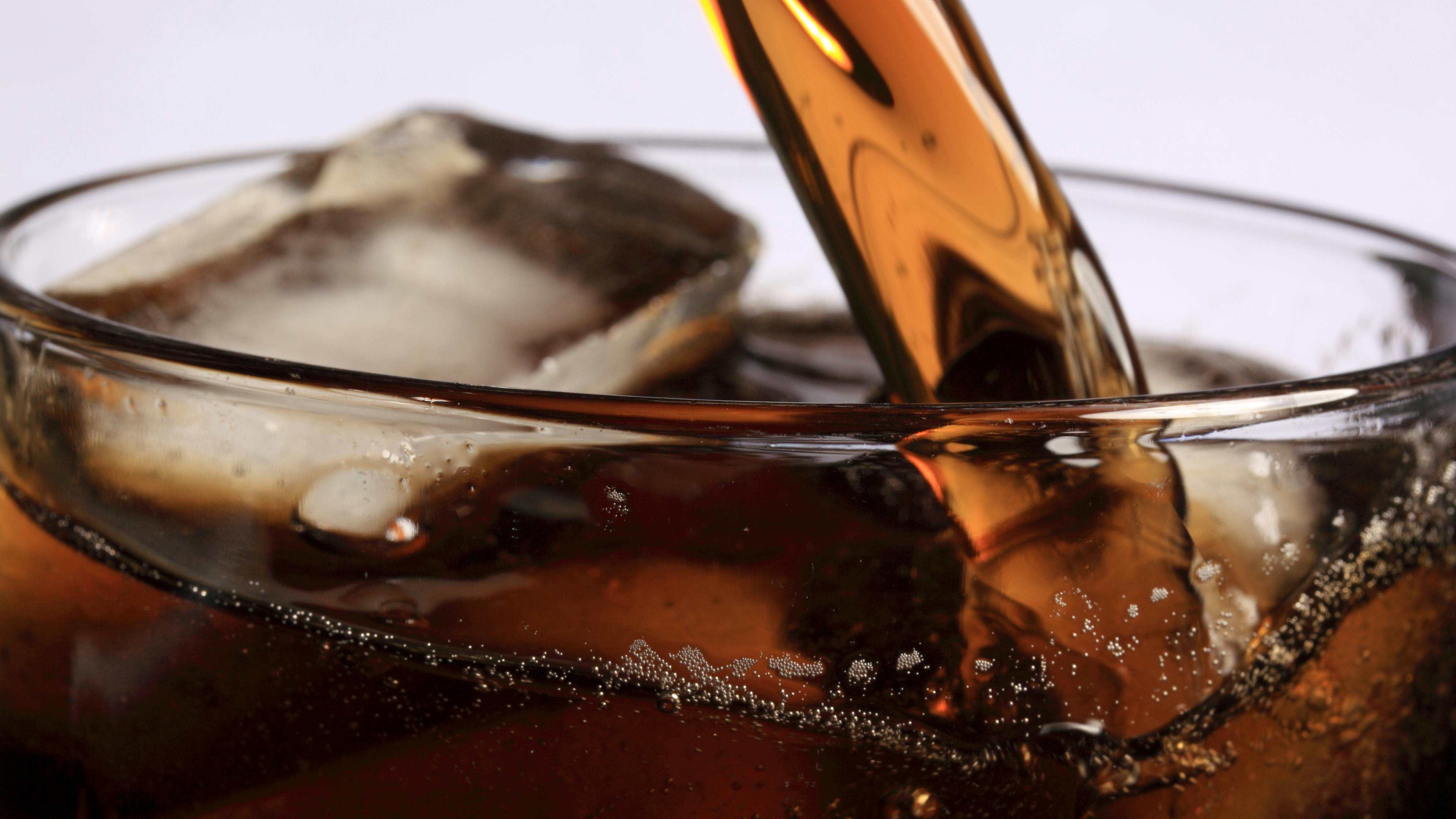 Photo of soda pouring into a glass of ice.