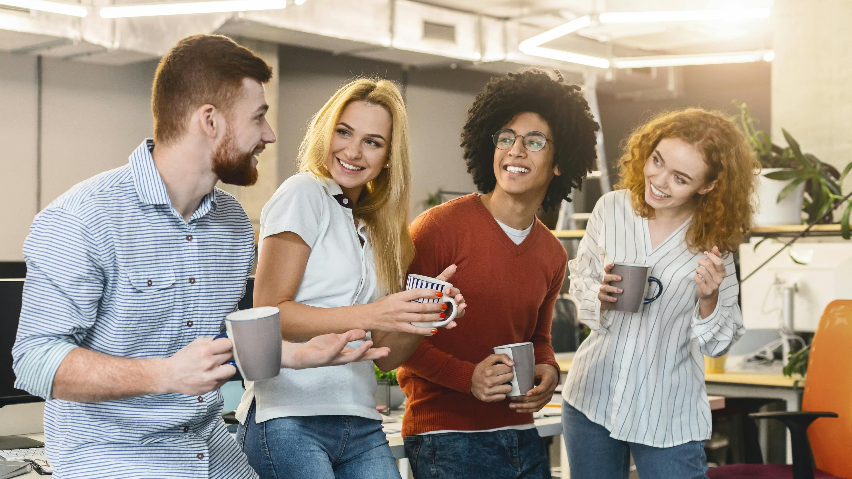 Group of Young Professionals Enjoying Coffee Break in Modern Office Space Together.