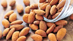 Raw almonds spilling out of small glass bowl Raw almonds spilling out of small glass bowl